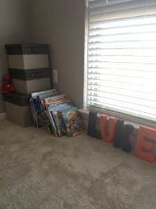 three bins of toys and a few children's book stacked on the floor in an empty bedroom