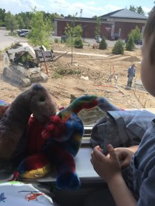 boy and stuffed dragon looking at landscape construction outside a second story window