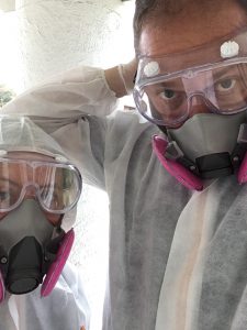 man and woman wearing coveralls and respirators to enter moldy home