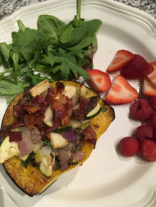 stuffed acorn squash on a plate with greens and berries