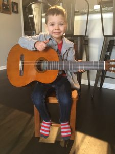 small child with guitar and smile on his face