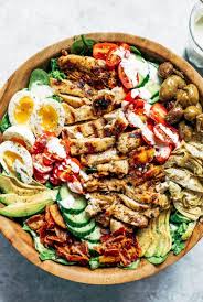 bowl full of salad with grilled chicken, boiled eggs, tomatoes, and greens