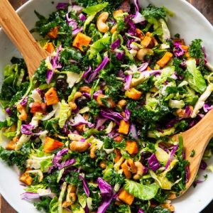 bright, colorful chopped salad with two wooden spoons in the bowl