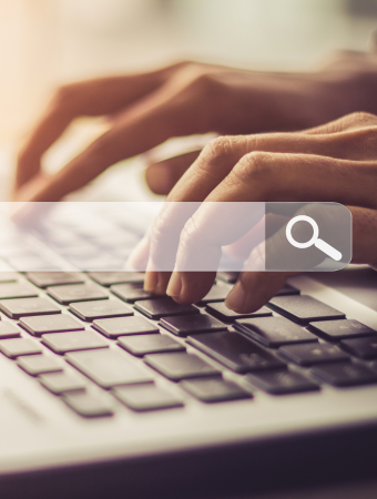 Hands typing on a computer with a serach bar visible